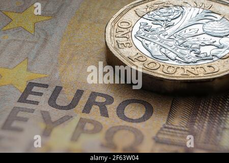 Une pièce de monnaie britannique d'une livre placée sur un billet de banque de 50 EUROS avec les mots visibles 'EURO' traduits dans différentes langues. Concept. Mise au point sélective. Macro. Banque D'Images