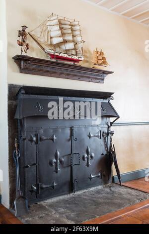 Portes en tôle noire avec détails fleur de lys en relief sur la cheminée Dans la salle de séjour à l'intérieur d'une ancienne maison de style Canadiana 1825 maison en pierre de champ Banque D'Images
