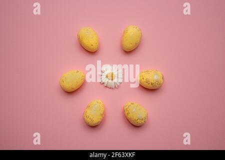 Œufs de Pâques jaunes disposés en cercle et fleurs au centre sur fond rose. Concept vacances de printemps Banque D'Images