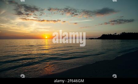 Surfez en douceur pendant un magnifique coucher de soleil au-dessus d'un océan calme. Banque D'Images