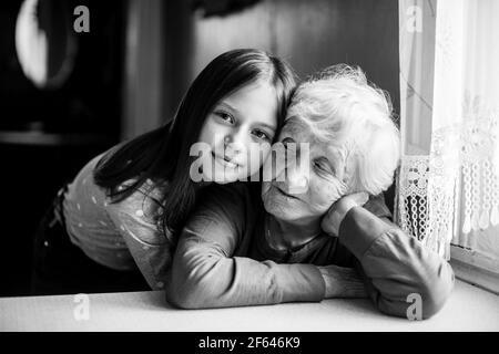 Une petite fille embrasse sa grand-mère. Portrait en noir et blanc. Banque D'Images