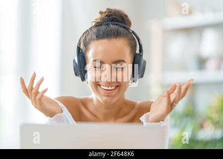 Une jeune femme utilise un ordinateur portable. Drôle de fille ayant le plaisir de rester à la maison. Banque D'Images