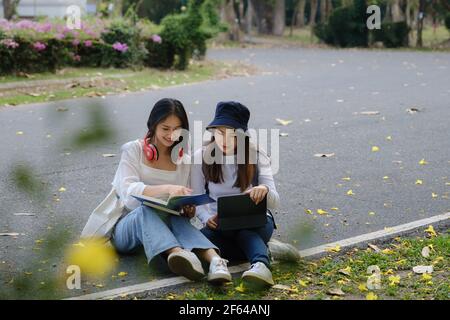 Deux étudiants sont assis à l'université pendant la lecture d'un livre et la communication. Étude, éducation, université, collège, concept de troisième cycle. Banque D'Images