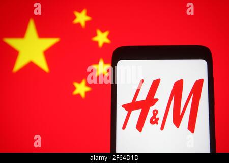 Ukraine. 30 mars 2021. Sur cette photo, le logo H&M (Hennes & Mauritz ) est visible sur l'écran d'un smartphone avec un drapeau chinois en arrière-plan. (Photo de Pavlo Gonchar/SOPA Images/Sipa USA) crédit: SIPA USA/Alay Live News Banque D'Images