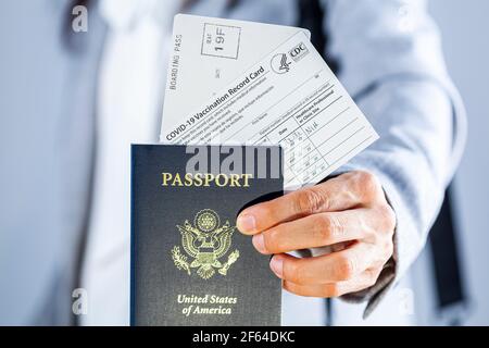 Clarksburg, Maryland, États-Unis 03-29-2021: Une femme d'affaires caucasienne présente ses documents de voyage à l'aéroport, y compris le passeport américain, la carte d'embarquement et COVID va Banque D'Images