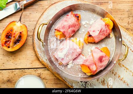 Morceaux de Tamarillo emballés et cuits avec du jambon et du bacon Banque D'Images