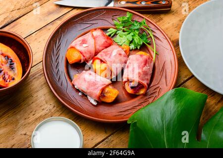 Morceaux de Tamarillo emballés et cuits avec du jambon et du bacon Banque D'Images