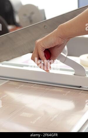 gros plan la main d'une femme appuie sur la poignée d'un manuel guillotine pour une machine dans une imprimerie ou une usine Banque D'Images