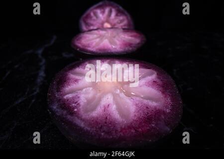 Une pomme bien mûre montrant les fruits colorés coupés en deux, un fruit populaire de saison aux Philippines. Banque D'Images