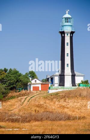 Phare projecteur à travers l'air de mer la nuit. Paysage marin au coucher du soleil. Banque D'Images