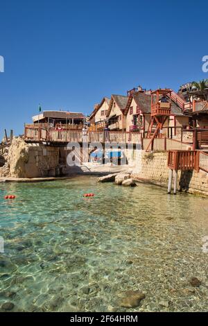 Pont sur la baie de Prajjet ou Anchor Bay au village de Popeye à Malte avec des acteurs représentant Bluto, Popeye et Olive Oyl. Banque D'Images