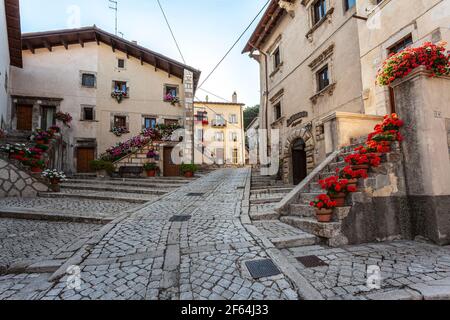 Route pavée de pavés dans l'ancien village de montagne de Pesostanzo. Marches et balcons décorés de pots de géraniums. Abruzzes Banque D'Images