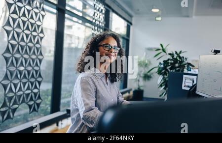 Portrait d'une femme d'affaires mûre portant un casque lorsqu'elle est assise dans son bureau. Représentant du service clientèle travaillant au bureau. Banque D'Images