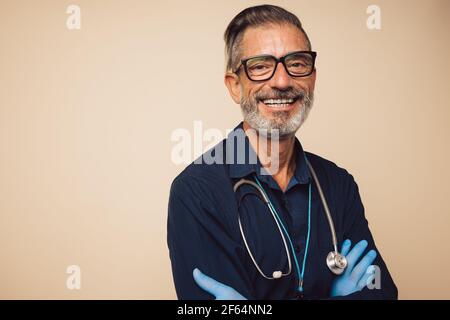 Portrait d'un médecin confiant avec stéthoscope portant des gants de protection. Médecin regardant la caméra et souriant avec ses bras croisés. Banque D'Images