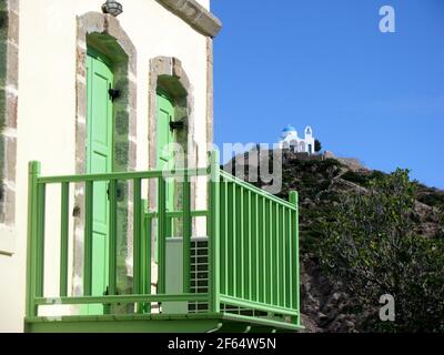 maison avec portes paintette vertes et balcon avec petite église En arrière-plan sur l'île de Nisyros en Grèce Banque D'Images