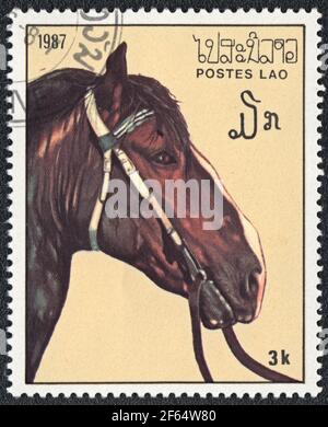 Timbre-poste montre un cheval brun harnais (Equus ferus cabalus) de la série: Chevaux pur-sang, Laos, 1987 Banque D'Images