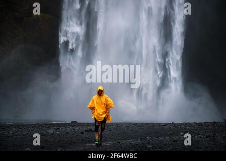 Le port d'un imperméable jaune touristiques promenades de la cascade de Skogafoss en Islande Banque D'Images