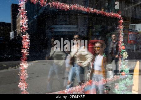 Les passants et les restes de Noël occupent encore la fenêtre d'une petite entreprise fermée dans le West End, lors du troisième confinement de la pandémie du coronavirus, le 29 mars 2021, à Londres, en Angleterre. Banque D'Images