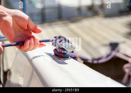 Homme main avec corde de bateau, yachtsman nouant le noeud de mer. Main humaine sur un bateau à voile ou un yacht noué, vue rapprochée Banque D'Images