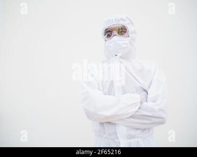 Portrait d'un homme asiatique confiant médecin ou scientifique dans l'uniforme de la suite PPE tout en repliant ses mains dans le fond blanc. Coronavirus ou COVID-19 con Banque D'Images