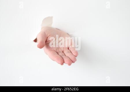 La main d'une femme sort par le trou du papier blanc Banque D'Images