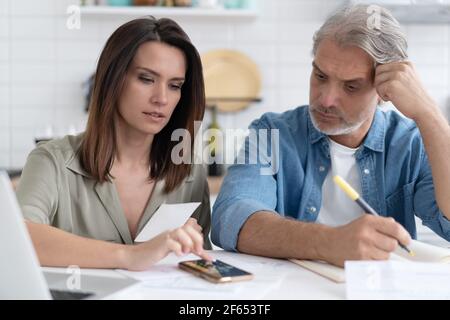 Un couple de familles stressé a reçu une notification d'hypothèque de dette, vérifiant les documents financiers Banque D'Images