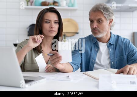 Un couple de familles stressé a reçu une notification d'hypothèque de dette, vérifiant les documents financiers Banque D'Images