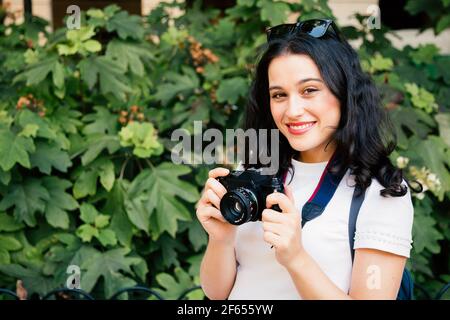 Jeune belle femme prenant des photos avec un appareil photo rétro un parc de la ville Banque D'Images