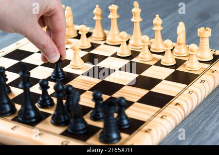 Main d'une femme commençant un jeu d'échecs. Concept de jouer aux échecs à la maison, passe-temps à la maison Banque D'Images