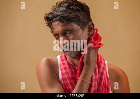Un fermier essuyant sa sueur avec un chiffon rouge Banque D'Images