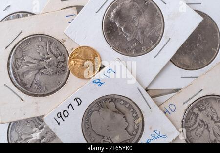 Vue rapprochée d'une collection de pièces de monnaie ancienne dans des emballages protecteurs avec une pièce de monnaie Liberty dorée en vrac sur le dessus. Banque D'Images