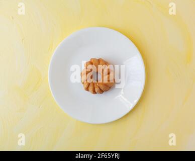 Vue de dessus d'un petit morceau de verre glacé sur une plaque blanche au-dessus d'un plan d'examen peint en jaune éclairé par une lumière de fenêtre. Banque D'Images