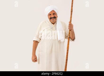 UN HOMME ADULTE SE TIENT DEBOUT AVEC LE BÂTON DANS LA MAIN AVANT DE L'APPAREIL PHOTO Banque D'Images