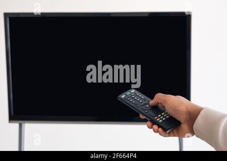 Homme noir regardant la télévision et utilisant la télécommande Banque D'Images