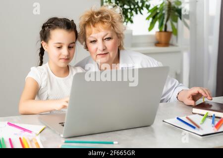 Femme tuteur ou parent d'accueil maman aidant mignon caucasien école enfant fille faisant des devoirs assis à la table. Divers nounou et enfant apprenant à écrire Banque D'Images