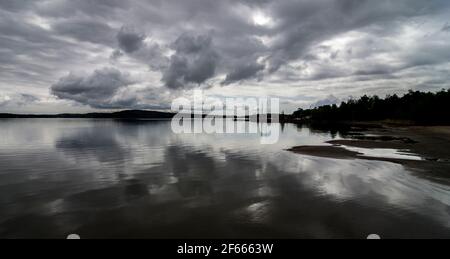 Un ciel orageux se reflète dans les eaux calmes de la mer Baltique à une crique près de Mariehamn, îles Aland, Finlande. Banque D'Images