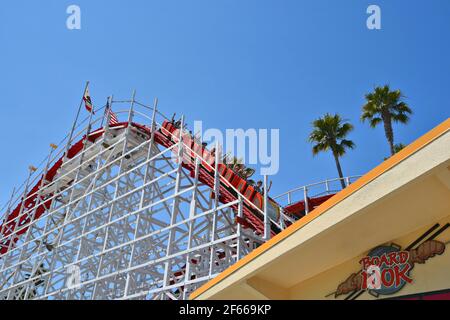 Vue panoramique sur les gens sur le Giant Dipper, les montagnes russes classiques en bois, point de repère du parc d'attractions de Santa Cruz en Californie, États-Unis. Banque D'Images