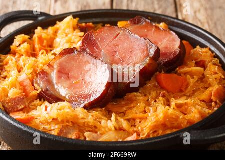 Podvarak de Sauerkraut cuit avec carottes, oignons, porc fumé et bacon dans la poêle sur la table. Horizontal Banque D'Images