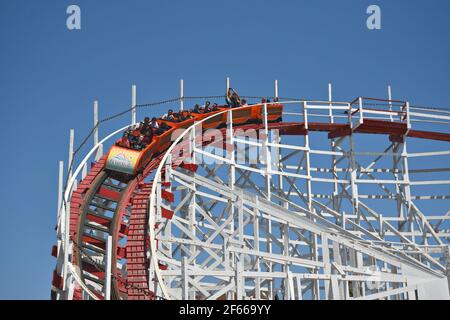 Vue panoramique sur les gens sur le Giant Dipper, les montagnes russes classiques en bois, point de repère du parc d'attractions de Santa Cruz en Californie, États-Unis. Banque D'Images