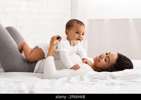 Maman noire jouant avec bébé couché sur son ventre à l'intérieur Banque D'Images
