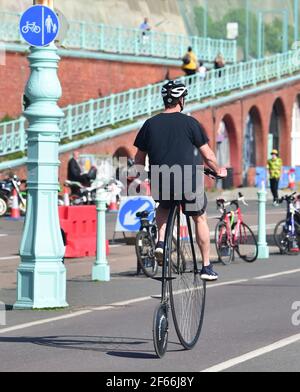 Brighton Royaume-Uni 30 mars 2021 - ce chap obtient une vue aérienne sur son penny farthing vélo le long de Brighton front de mer le jour le plus chaud de l'année jusqu'à présent avec des températures atteignant le milieu de 20 centigrade dans certaines parties du Sud-est : crédit Simon Dack / Alay Live News Banque D'Images