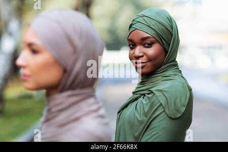 Deux femmes musulmanes diverses qui se posent en portant le hijab debout à l'extérieur Banque D'Images