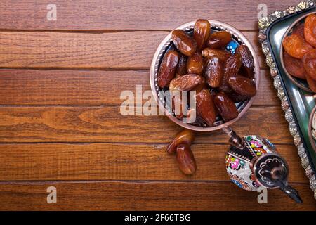 Assiette avec dattes, cafetière sur table en bois brun. Arrière-plan du ramadan. Vue de dessus. Banque D'Images