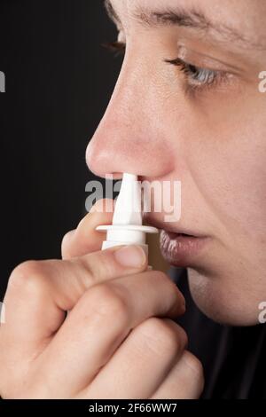 une femme malade souffle de spray nasal dans son nez. Banque D'Images