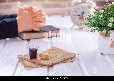 Jeune femme priant et prenant la communion - le vin et les symboles du pain de Jésus Christ sang et corps avec la Sainte Bible. Pâque de Pâques Banque D'Images