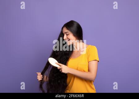 Jeune femme indienne se brossant les cheveux longs avec la peigne en bois Banque D'Images