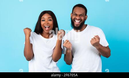 Portrait d'un heureux couple noir célébrant la victoire avec des poings levés Banque D'Images
