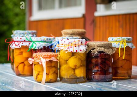 Compotes de fruits faits maison sur une table dans le jardin, concentration sélective. Aliments conservés en pots. Prune, pêche, abricot, compotes cerise Banque D'Images