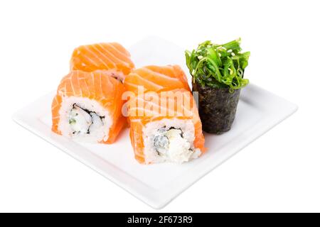 Roulé à sushis au saumon avec crabe des neiges et concombre. Servi avec du gunkan aux algues. Macro. La photo peut être utilisée comme arrière-plan entier. Banque D'Images