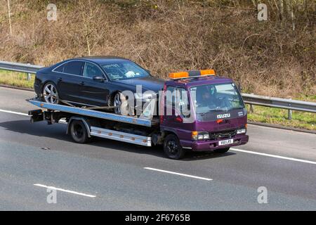 1999 90s années quatre-vingt-dix Isuzu NPR 65 P 3856cc diesel HCV remorquage d'une voiture endommagée avec sac gonflable déployé et capot bloqué; remorque de dépannage de voiture d'accident de route; service de dépannage commercial de 24 heures; sur l'autoroute M61, Royaume-Uni Banque D'Images